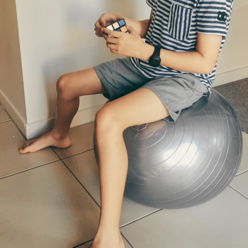 A child sitting on an exercise ball while working on a puzzle